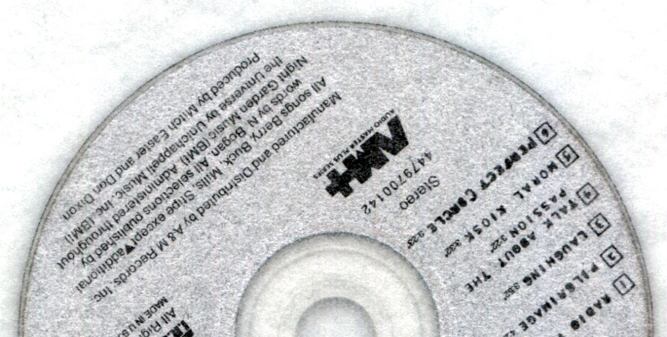 When scanned through tracing paper, there are no rainbows on the shiny metal surfaces of the CD, but the paper grain is visible.